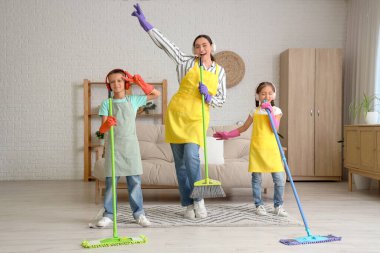 Anne ve çocukları kulaklıkla evde temizlik yaparken eğleniyorlar.