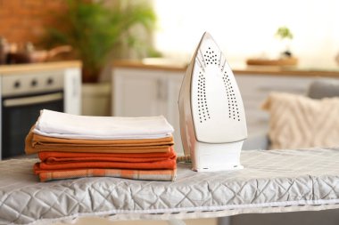 Ütü masasında demir ve çarşaf yığını, yakın çekim.