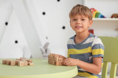 Evde pijamalı, tahta küplerle oynayan sevimli, mutlu bir çocuk.