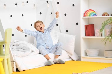 Pijamalı küçük şirin bir çocuğun evde yatakta esnediği bir sabah.