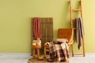 Oturma odasının içinde koltuk, katlanan ekran ve balkabaklarıyla