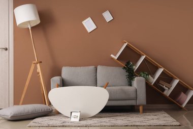 Gri kanepeli dağınık oturma odasının içi ve depremden sonra mobilyaları ters dönmüş.