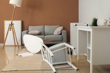 Gri kanepeli dağınık oturma odasının içi ve depremden sonra mobilyaları ters dönmüş.