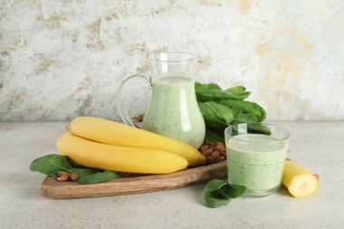 Beyaz arka planda muz ve badem fıstıklı taze ıspanaklı smoothie.