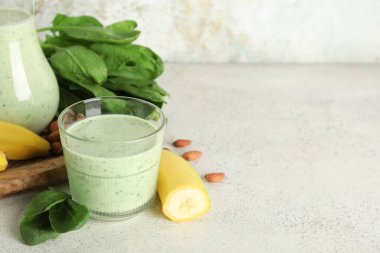 Beyaz arka planda muz ve badem fıstıklı taze ıspanaklı smoothie.