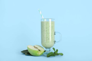 Mavi arka planda elma ve nane aromalı taze ıspanaklı smoothie.