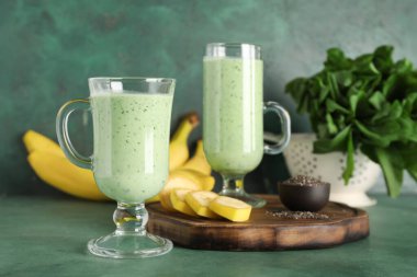 Muzlu taze ıspanaklı smoothie ve yeşil arka planda bir kase chia tohumu.