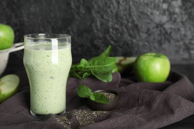Bir bardak taze ıspanaklı smoothie ve siyah arka planda bir kase chia tohumu.