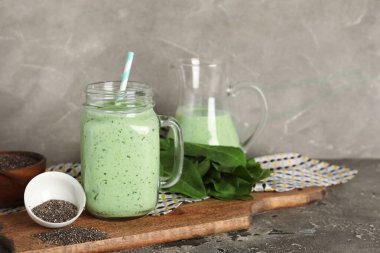 Mason kavanozu taze ıspanaklı smoothie ve gri arka planda chia tohumlu kase.