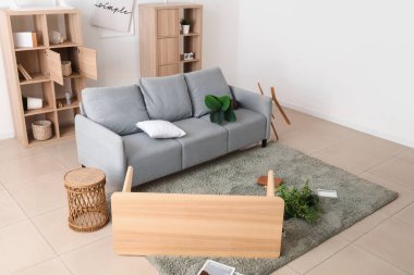 Gri kanepeli dağınık odanın içi ve depremden sonra mobilyaları ters dönmüş.