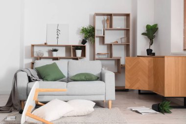 Gri kanepeli dağınık odanın içi ve depremden sonra mobilyaları ters dönmüş.