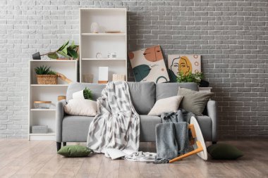 Gri tuğla duvarın yanındaki depremden sonra mobilyaların devrildiği dağınık bir odanın içinde.