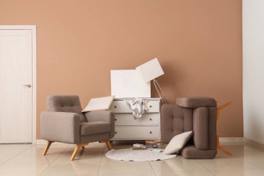 Koltuklu dağınık odanın içi ve bej duvarın yanındaki depremden sonra mobilyaları ters dönmüş.