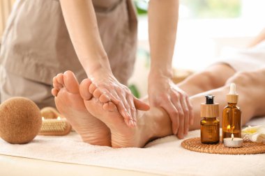 Kozmetik ürünleri olan güzel genç bir kadın kaplıca salonunda ayak masajı yaptırıyor.