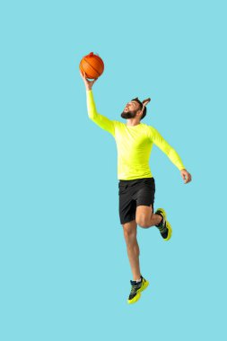 Ren geyiği boynuzlu genç adam Noel hediyesi olarak topuyla mavi arka planda zıplıyor.