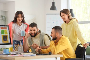 Tekerlekli sandalyede çalışan tasarımcı takımı.