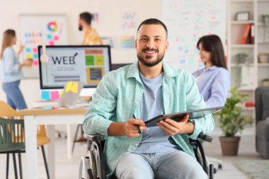 Ofisinde grafik tabletle tekerlekli sandalyede oturan erkek tasarımcı.