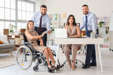 Tekerlekli sandalyede çalışan bayan meslektaşlarıyla birlikte çalışan tasarımcılar.