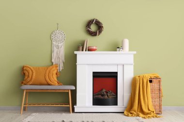 Oturma odasının içinde yumuşak bank, şömine ve sepet var.