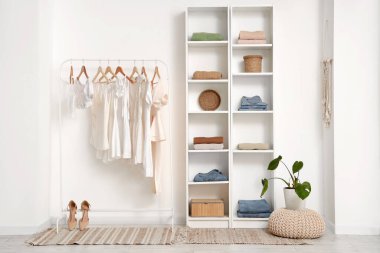 Farklı kadın kıyafetleriyle aydınlık soyunma odasının şık bir iç mekanı.