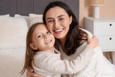 Anne ve küçük kızı yatak odasında gülümsüyor.