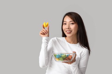 Gri arka planda renkli fal kurabiyeleri olan genç Asyalı kadın.