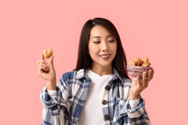 Pembe arka planda şans kurabiyeleri olan genç Asyalı kadın.