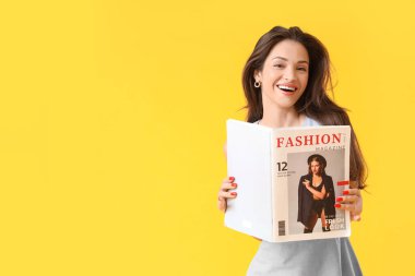 Sarı arka planda moda dergisiyle güzel bir genç kadın.