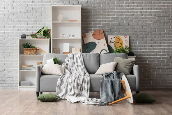 Gri tuğla duvarın yanındaki depremden sonra mobilyaların devrildiği dağınık bir odanın içinde.