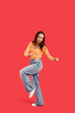 Kırmızı arka planda dans eden mutlu orta yaşlı kadın