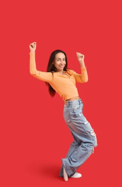 Kırmızı arka planda dans eden mutlu orta yaşlı kadın