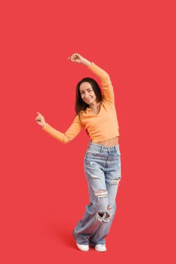 Kırmızı arka planda dans eden mutlu orta yaşlı kadın