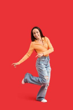 Kırmızı arka planda dans eden mutlu orta yaşlı kadın