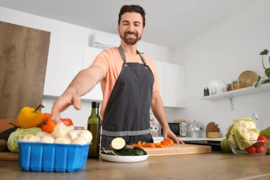 Mutfakta taze sebze pişiren yakışıklı sakallı adam.