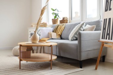 Gri kanepe, otlar ve kitaplarla aydınlık oturma odasının içinde.