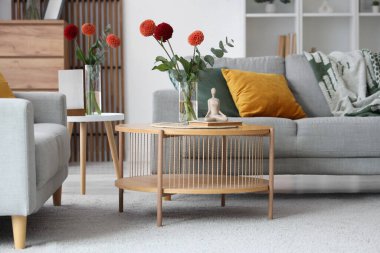 Gri kanepeleri ve kahve masasında güzel çiçekleri olan şık bir oturma odası.