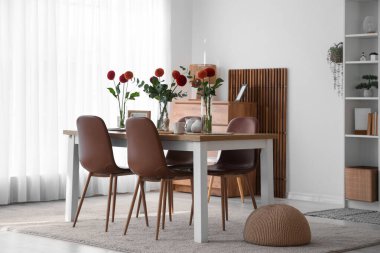 Evdeki yemek masasında vazolar, çiçek ve çay.