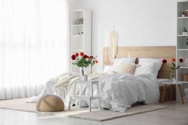 Yatakodasındaki komodinlerin üzerinde yıldız çiçeği olan vazolar.