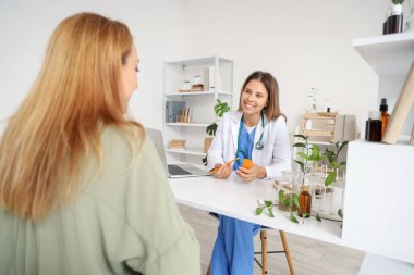 Kadın homeopatik doktor ofisteki hastaya ilaç veriyor.