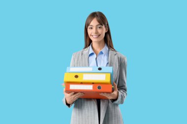 Mavi arka planda klasörleri olan genç bir iş kadını