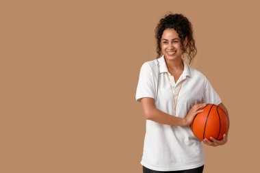 Bej arka planda topu olan Afro-Amerikan bayan basketbol antrenörü.