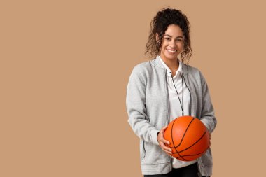 Bej arka planda topu olan Afro-Amerikan bayan basketbol antrenörü.