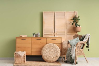 Hasır koltuğu, rahat battaniyesi ve ahşap dolabı olan şık bir oturma odası.