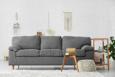 Modern oturma odası içi gri kanepe ve sehpanın üzerinde bir yığın kitap.