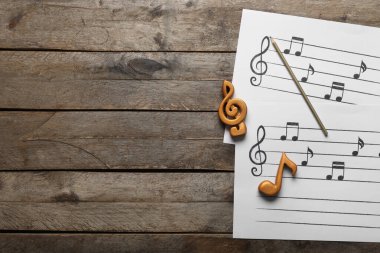 Müzik kağıtları, not tabelaları ve tahta arka plandaki kalem.