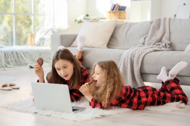 Kurabiyeli şirin kız kardeşler kış günü evde çizgi film izliyorlar.