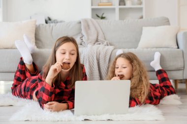 Kurabiyeli şirin kız kardeşler kış günü evde çizgi film izliyorlar.