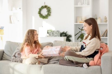 Küçük kız, kış günü kız kardeşine evde hediye veriyor.