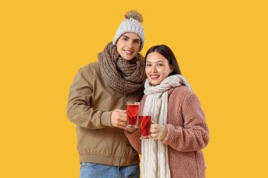 Sarı arka planda lezzetli şarap kadehleriyle mutlu bir çift.