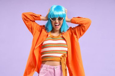 Mor arka planda mavi peruklu güzel, genç ve mutlu bir kadın.